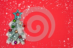 Decorative Christmas tree with Christmas ornaments on red background with snow texture. Copy space