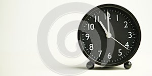 Decorative close-up black analog alarm clock for 10 o`clock isolated on white background with abstract copy space, start time of