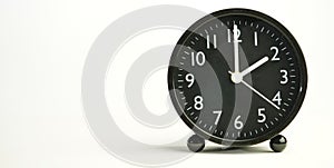 Decorative close-up black analog alarm clock for 2 o`clock, separate white background with copy space