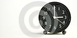 Decorative close-up black analog alarm clock for 3 o`clock or 15 o`clock, separate white background with copy space