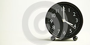 Decorative close-up black analog alarm clock for 4 or 16 o`clock, separate white background with copy space