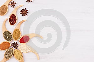 Decorative colorful border of multicolored asian spices and anise star, clove on white wooden background, copy space.