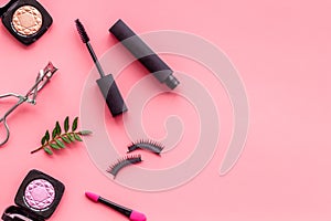 Decorative cosmetic set with lash curler and mascara on pink woman desk background top view mock up