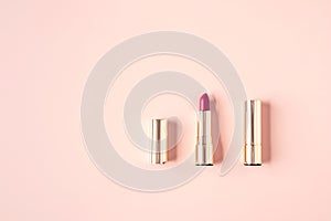 Decorative cosmetics composition of mockup lipsticks in golden casings on pastel pink background. Cosmetics concept