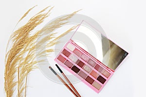 Decorative cosmetics, eye shadow, makeup brushes and a bouquet of dry grass