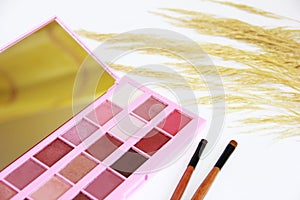 Decorative cosmetics, eye shadow, makeup brushes and a bouquet of dry grass