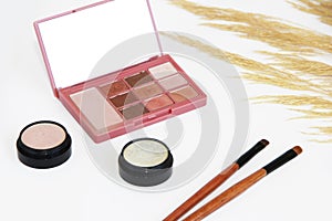 Decorative cosmetics, eye shadow, makeup brushes and a bouquet of dry grass