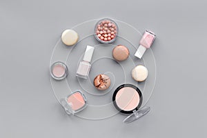 Decorative cosmetics for make-up with macaroon cookies on gray tabletop background pattern