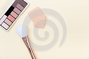 Decorative cosmetics, makeup products and brushes on light pink background