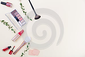 Decorative cosmetics, makeup products and brushes on light pink background