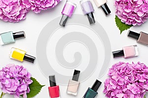 Decorative cosmetics, nail polish. Set of different varnishes for manicure nails on light background with flowers of pink