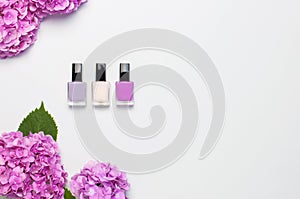 Decorative cosmetics, nail polish. Set of different varnishes for manicure nails on light background with flowers of pink