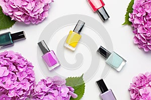 Decorative cosmetics, nail polish. Set of different varnishes for manicure nails on light background with flowers of pink