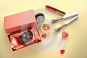 Decorative cosmetics with perfume and blank card on light background