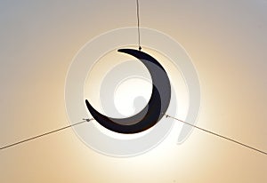 Decorative crescent moon supported with strings with sun besides