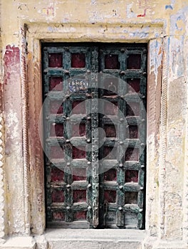 A decorative dark color door gate with square pattern design of local residence in narrow alley between colourful houses in