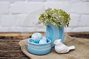 Decorative dyed easter eggs in blue pot with green hydrangea in skyey ceramic vasa and white ceramic bird on brown wooden