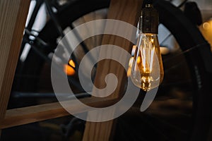 Decorative edison style light bulb against wooden stairs and bicycle wheel. bokeh background and copy space. lightning decoration