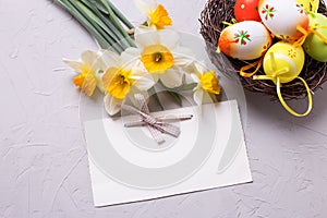 Decorative eggs in nest and yellow daffodils or narcissus flowe