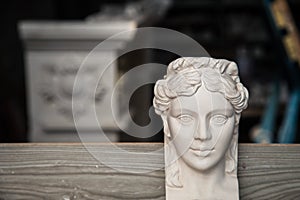 Decorative element made of plaster with a face. The creation of the moldings in the workshop. Selective focus