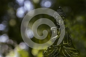 Decorative figure of plaster of Buddha in complete meditation on green background