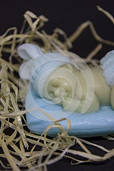 decorative figure of a sleeping baby on a blue pillow in straw