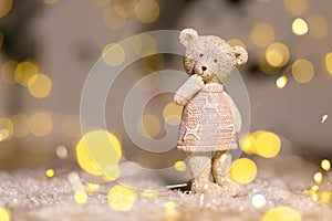 Decorative figurines of a Christmas theme. Figurine of a cute teddy bear girl in a sweater with deers. Festive decor, warm bokeh