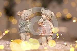 Decorative figurines of a Christmas theme. Figurine of a cute teddy bear girl in a sweater with deers. Festive decor, warm bokeh