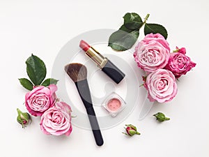 Decorative flat lay composition with cosmetics and flowers. Top view on white background