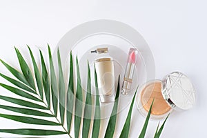Decorative flat lay composition with cosmetics and green tropic leaf. Flat lay, top view on white background