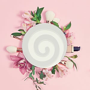 Decorative flat lay composition with makeup products, cosmetics and flowers. Flat lay, top view on pink background