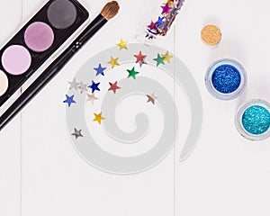 Decorative flat lay composition with makeup products, cosmetics and glass jars with decorative multi-colored stars. Flat