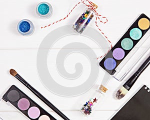 Decorative flat lay composition with makeup products, cosmetics and glass jars with decorative multi-colored stars. Flat