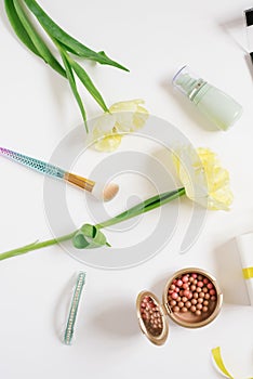 Decorative flatlay composition with make up products, cosmetics and flowers. Flat lay, top view on white background