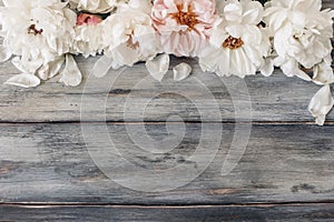 Decorative floral frame, banner made of pink and white peonies flowers. Old grey wooden table background. Empty copy