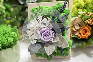 Decorative floristic arrangement of artificial flowers and stabilized moss