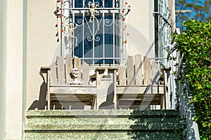 Decorative front porch with deal chairs and visible window with bars and beige stucco house or home exterior