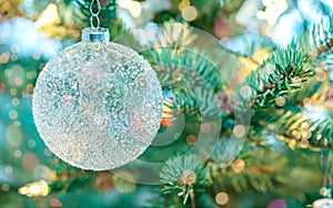 Decorative glass ball on blurred background of christmas tree and holiday lights