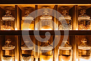 Decorative glass jars with spices on the kitchen shelf. Warm tint.