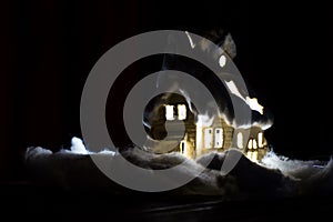 Decorative glowing house on a black background. Christmas decorations, a house, snow.