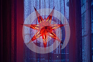 Decorative glowing star of Bethlehem in the window on Christmas Eve