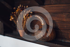 Decorative gourd perched on a shelf with a complementary potted plant featuring vibrant flowers.