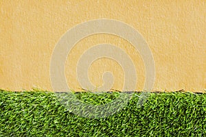 Decorative green grass artificial nature patterns on light brown concrete wall texture for background and space