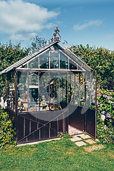 Decorative greenhouse in landscaped garden in summer