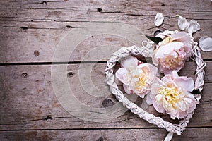 Decorative heart and pink peonies flowers on aged wooden backgr