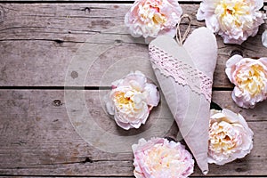 Decorative heart and pink peonies flowers on aged wooden backgr