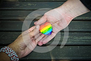 Decorative Heart with rainbow stripes in male hands. LGBT pride flag, symbol of lesbian, gay, bisexual, transgender for social