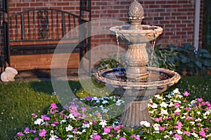 Decorative home water fountain in a bed of flowers