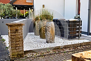 Decorative landscape. Several ceramic vases with plants on white stones in front of a house in Germany