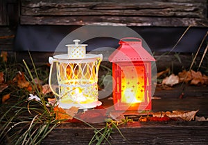 Decorative lantern with burning candle in autumn park at evening.